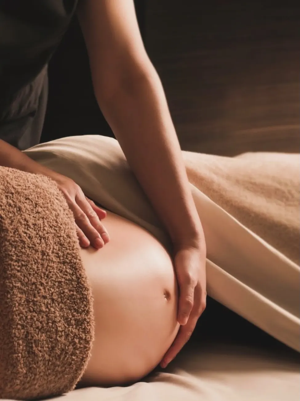 Massagem pré-natal: as mãos da terapeuta pousadas na barriga de uma grávida